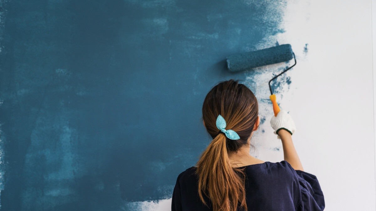 woman holding roller to paint walls blue
