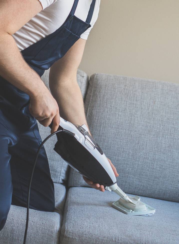 a man steam cleaning a couch