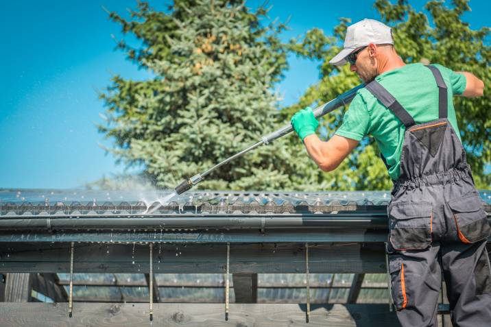 a professional cleaning gutters with a pressure washer